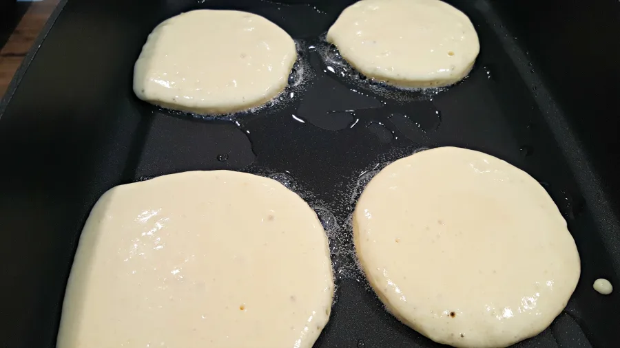 four pancakes frying in a pan.