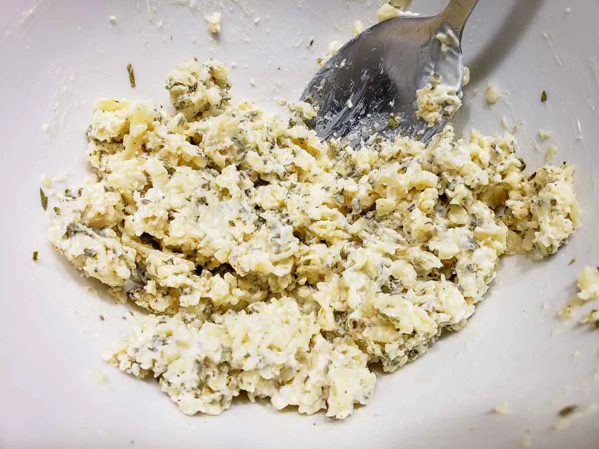 Parmesan cheese, butter, mayonnaise, chives, season salt, dried basil, and black pepper mixed in a bowl.