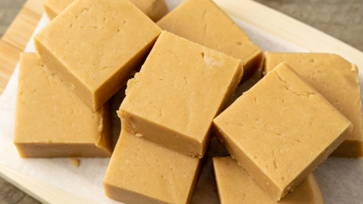 Creamy Peanut Butter Fudge stacked on parchment paper.