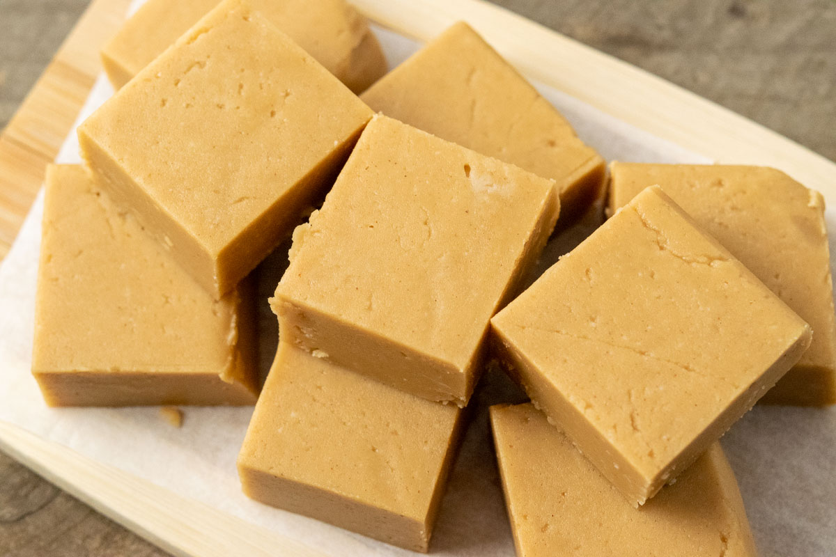 Creamy Peanut Butter Fudge stacked on parchment paper.