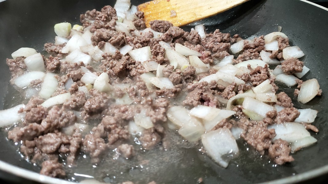ground beef and onions cooking in a skillet.