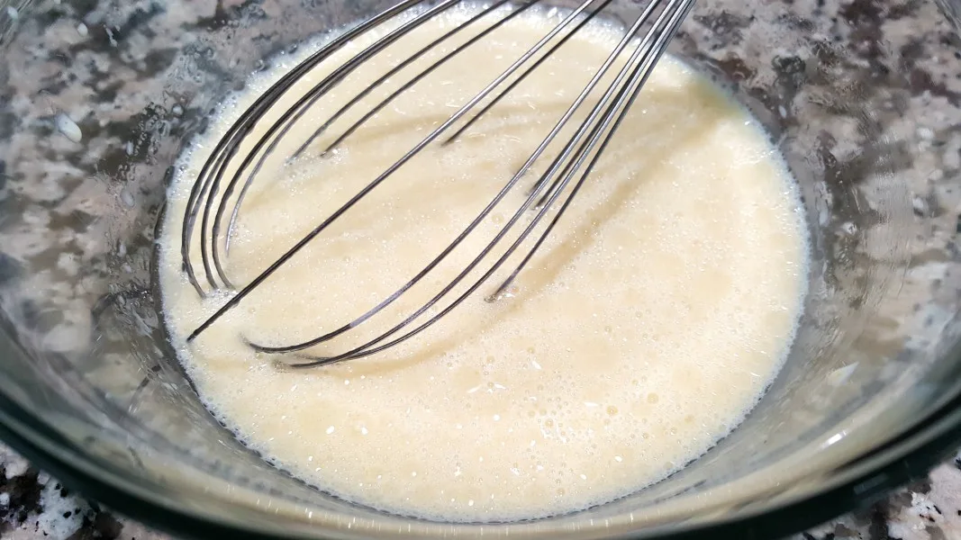 egg yolks, milk, oil, and vanilla whisked in a bowl.