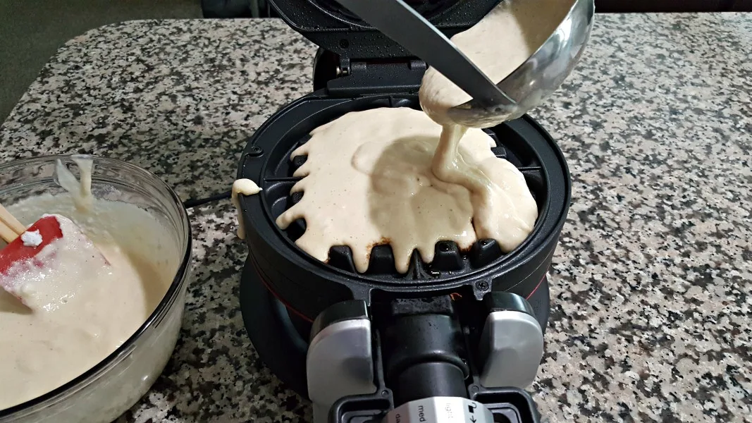 waffle batter being poured into a waffle iron.