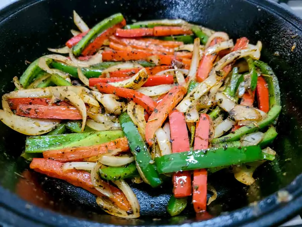 bell peppers, onions, and seasoning cooking in a skillet.