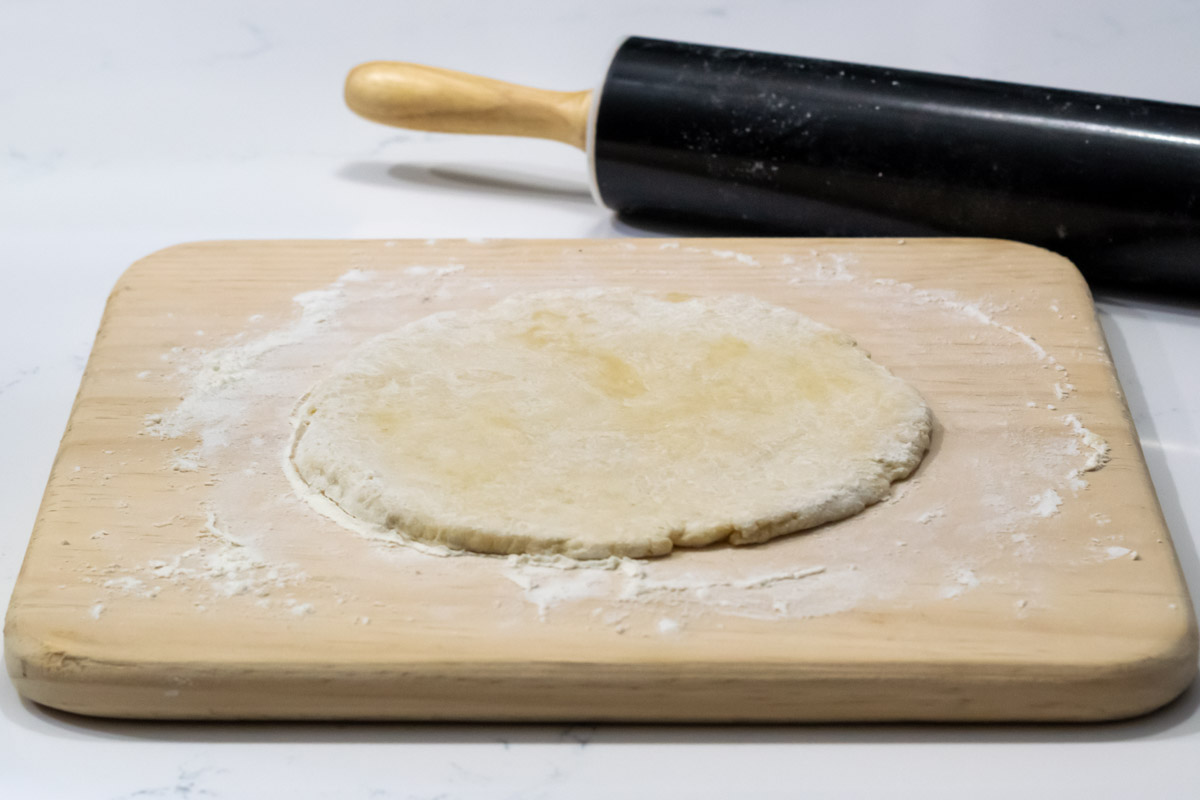 dough rolled out into a circle with a rolling pin.