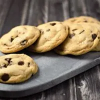 Soft Batch Chocolate Chip Cookies laying on a cutting board.