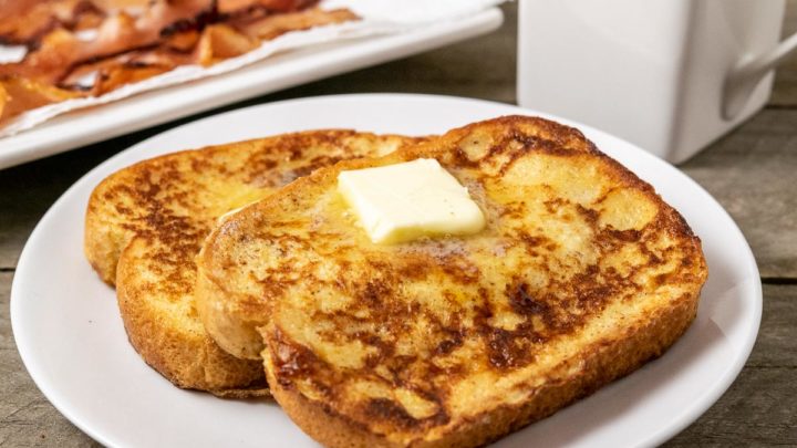 Thick French Toast slices on a plate topped with butter and syrup.