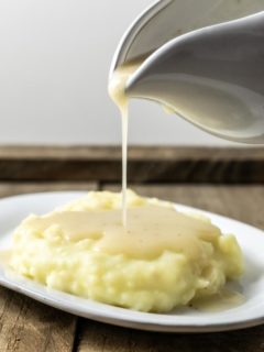 Homemade Chicken Gravy being poured over mashed potatoes.