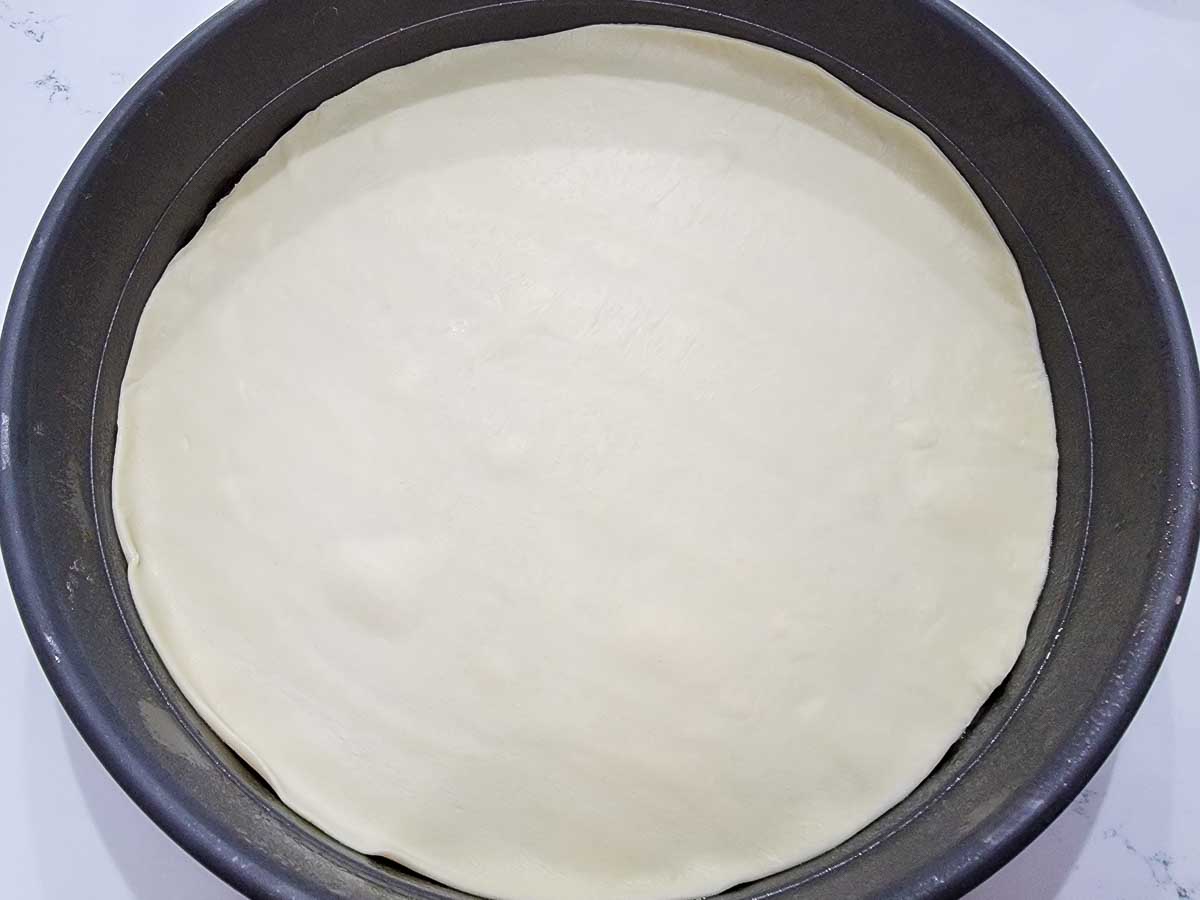 round pizza dough in a round pizza pan.