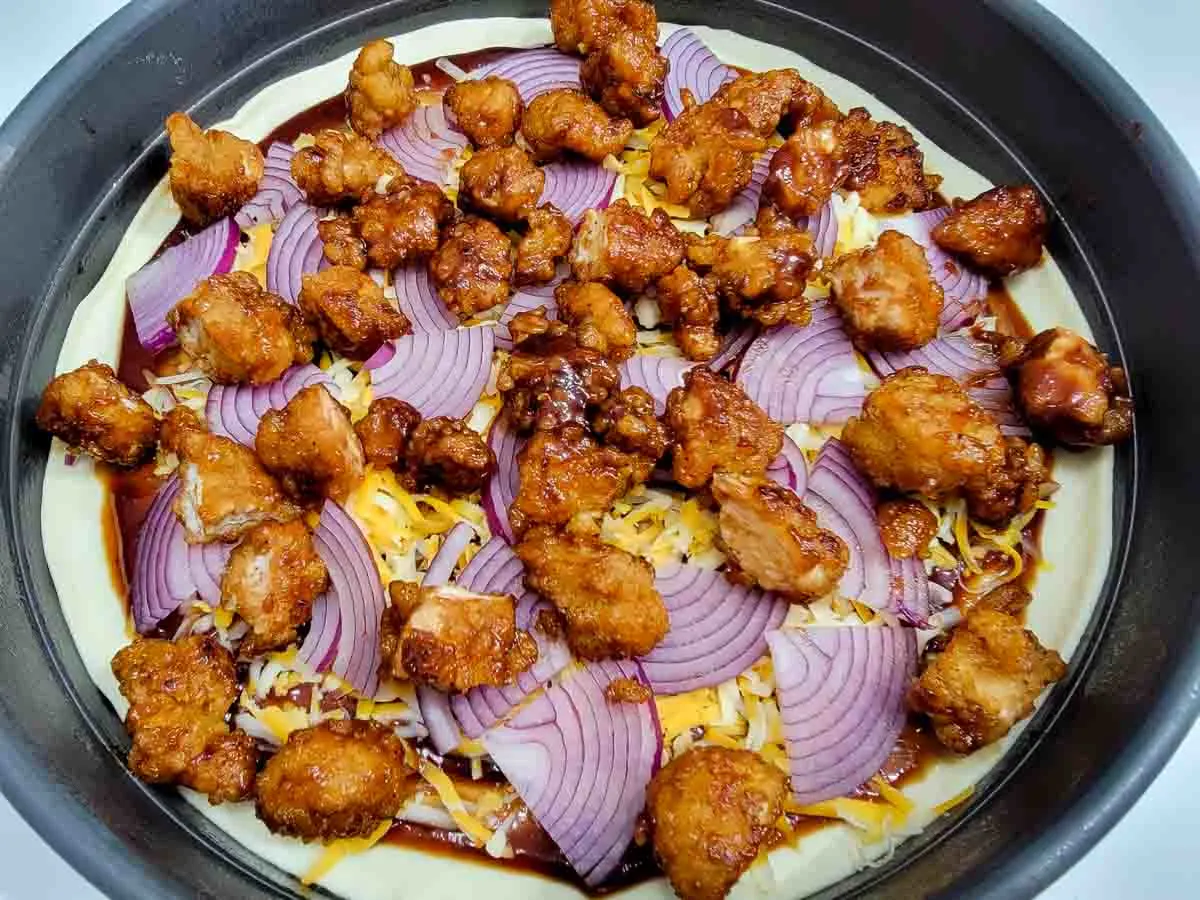 bbq popcorn chicken added to the top of the uncooked pizza.