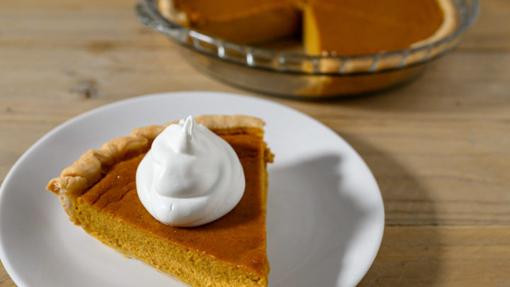 A slice of Easy Pumpkin Pie Recipe without Evaporated Milk topped with whipped cream.