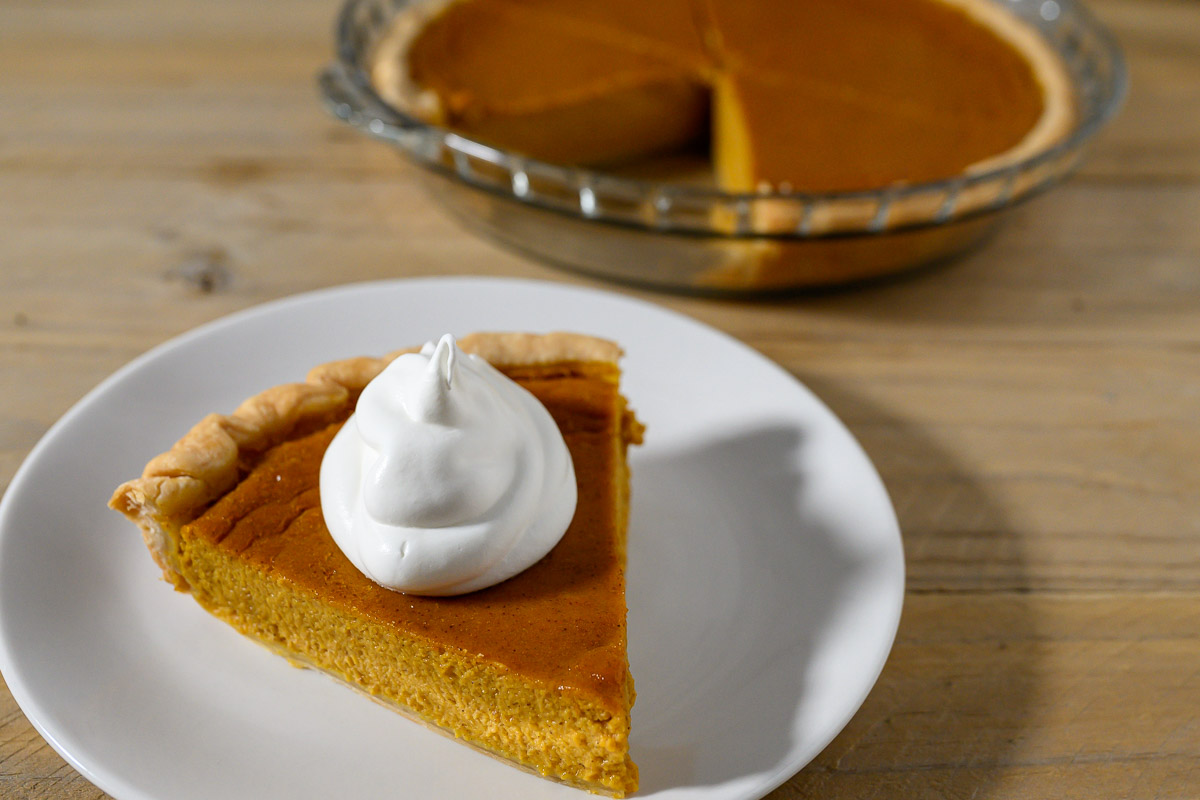 A slice of Easy Pumpkin Pie Recipe without Evaporated Milk topped with whipped cream.
