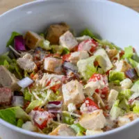 Chicken Parmesan Salad in a bowl topped with vinaigrette.