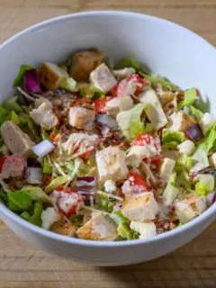 Tuscan Garden Chicken Salad in a bowl topped with salad dressing.