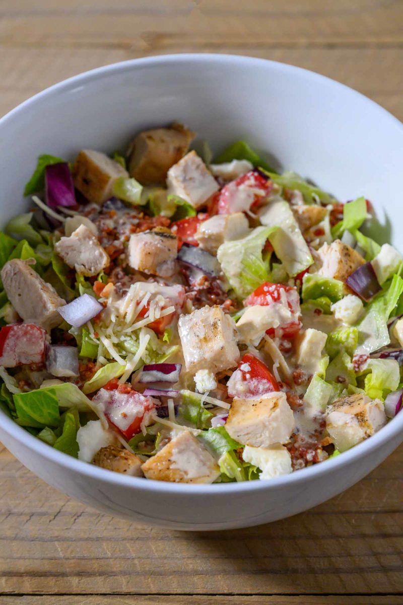 Tuscan Garden Chicken Salad in a bowl topped with salad dressing.