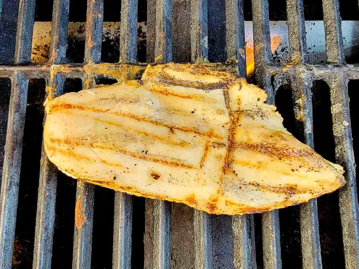 boneless chicken breast cooking on a gas grill.