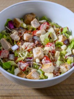 Tuscan Garden Chicken Salad in a bowl topped with salad dressing.