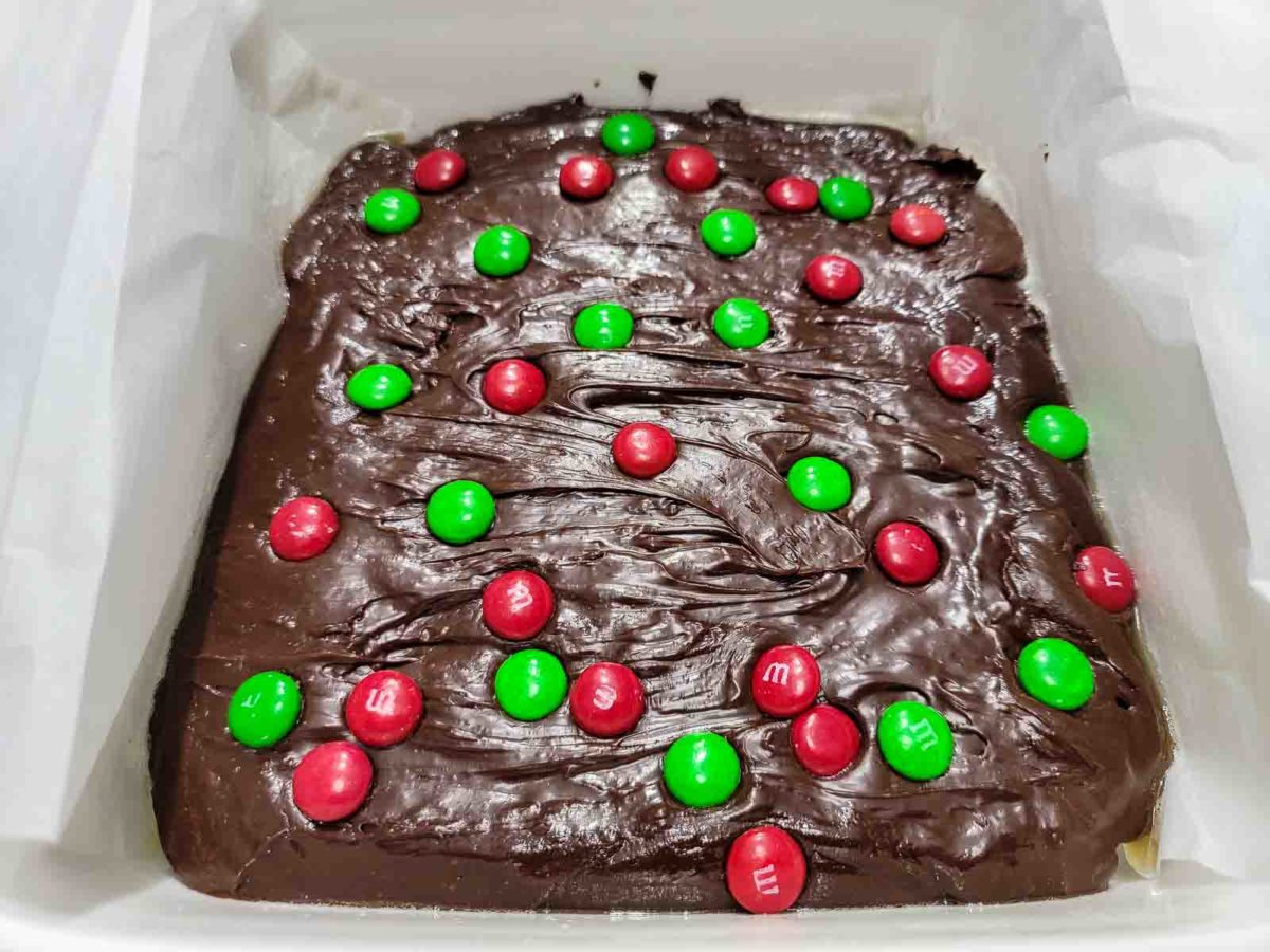 easy christmas fudge topped with red and green m&m's in an 8x8 inch baking dish.