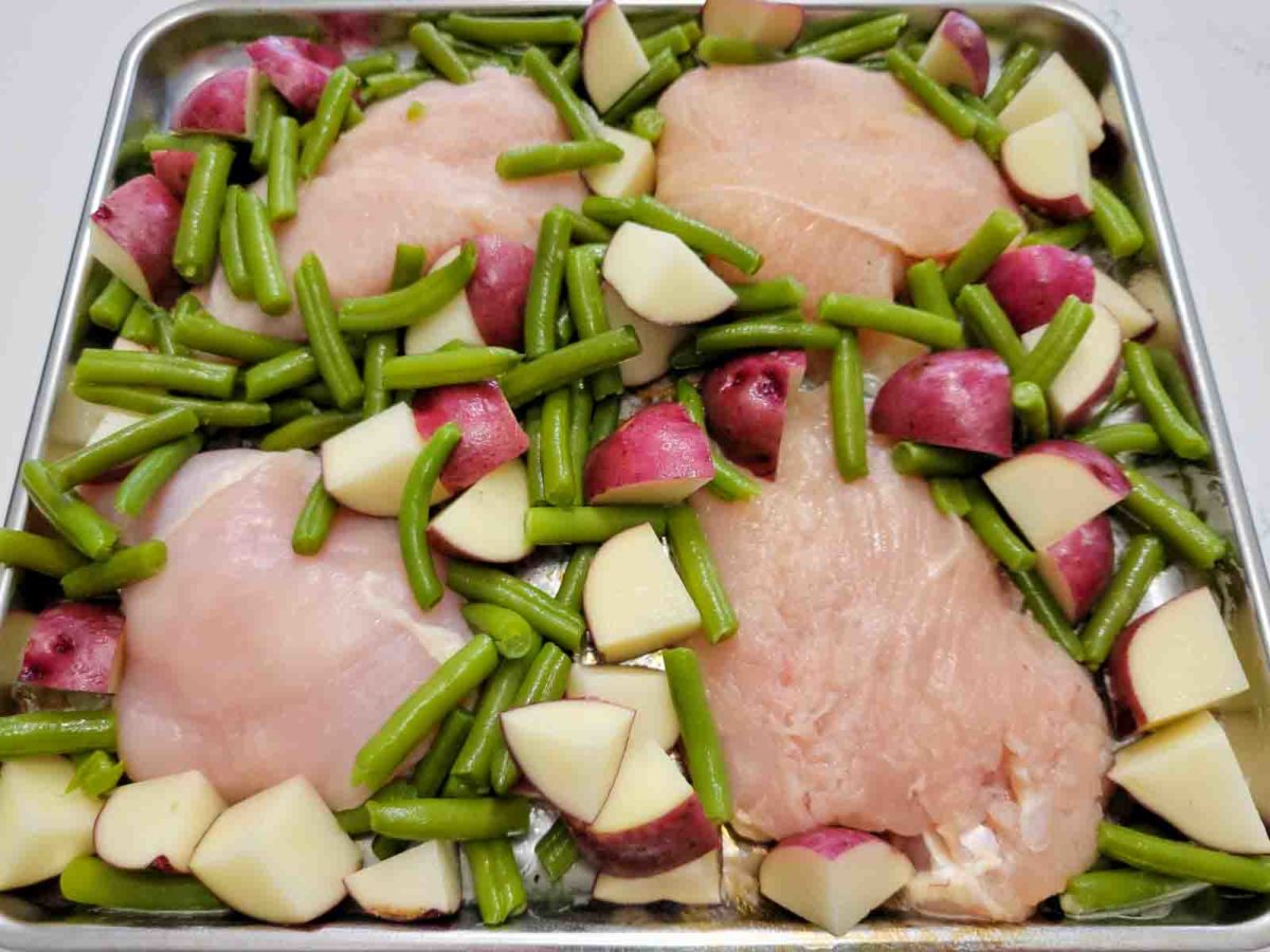 a sheet pan filled with italian tray bake with boneless chicken, red potatoes and green beans.