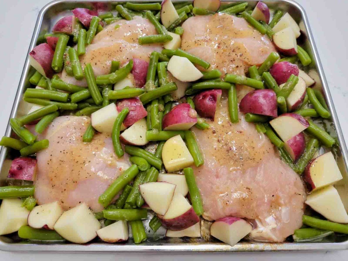 italian dressing chicken on a sheet pan filled with boneless chicken, red potatoes and green beans.