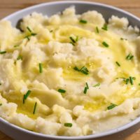 Homemade Mashed Potatoes without Milk topped with melted butter and chives.