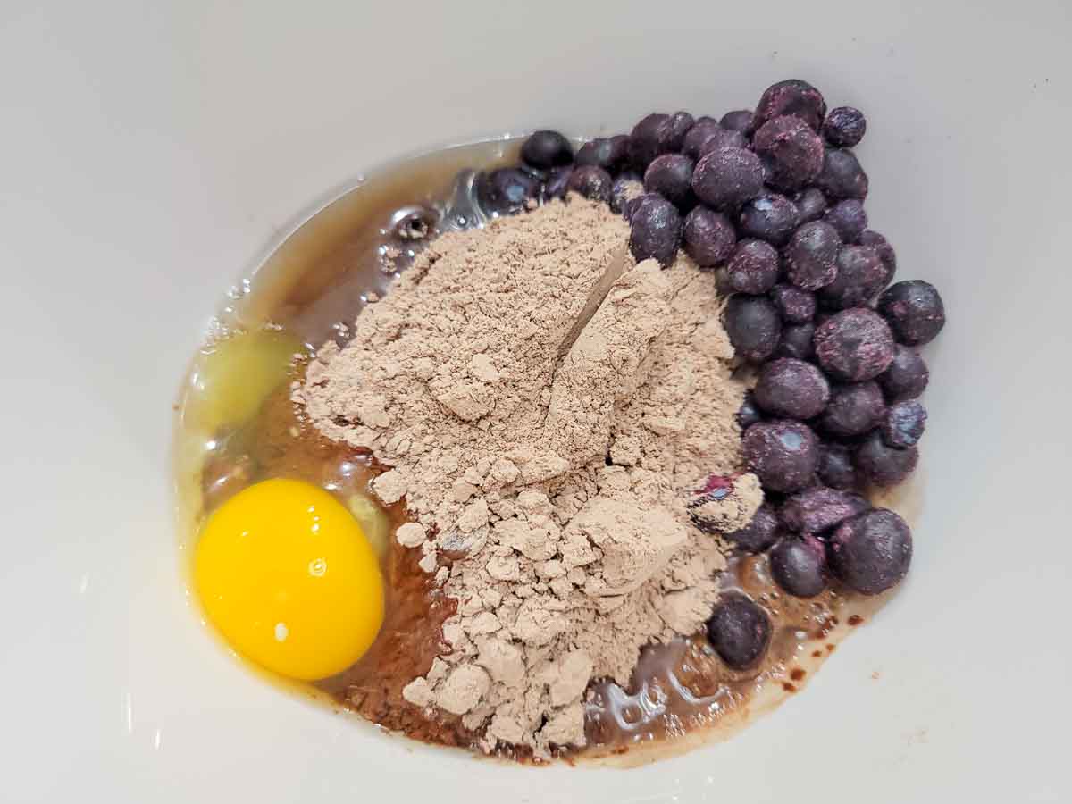 egg, brownie mix, water, oil, and blueberries in a bowl.