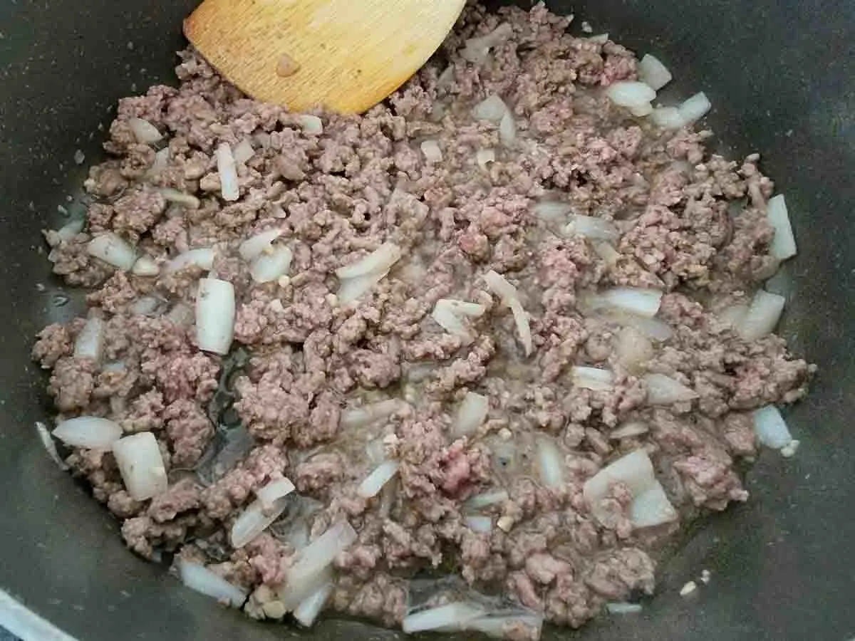 ground beef and onions cooking in a pan.