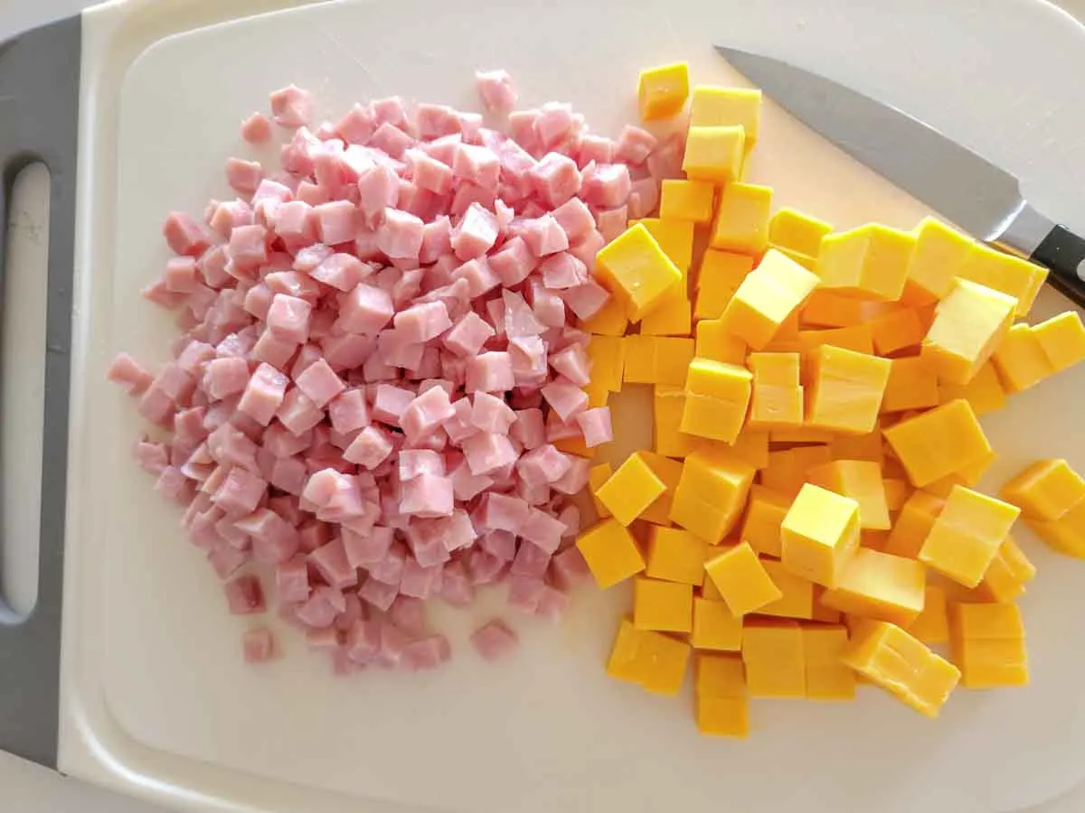 diced ham and cheddar cheese on a cutting board.