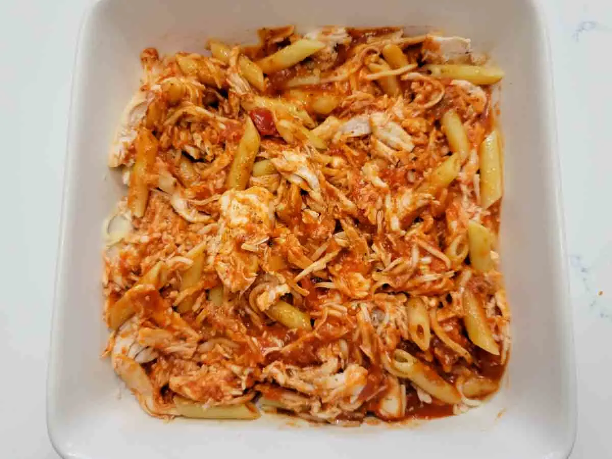 penne pasta, chicken, and sauce in a baking dish.