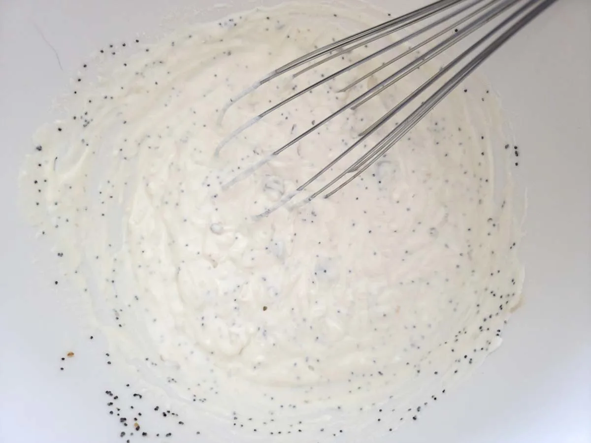 creamy white poppy seed sauce whisked in a bowl.
