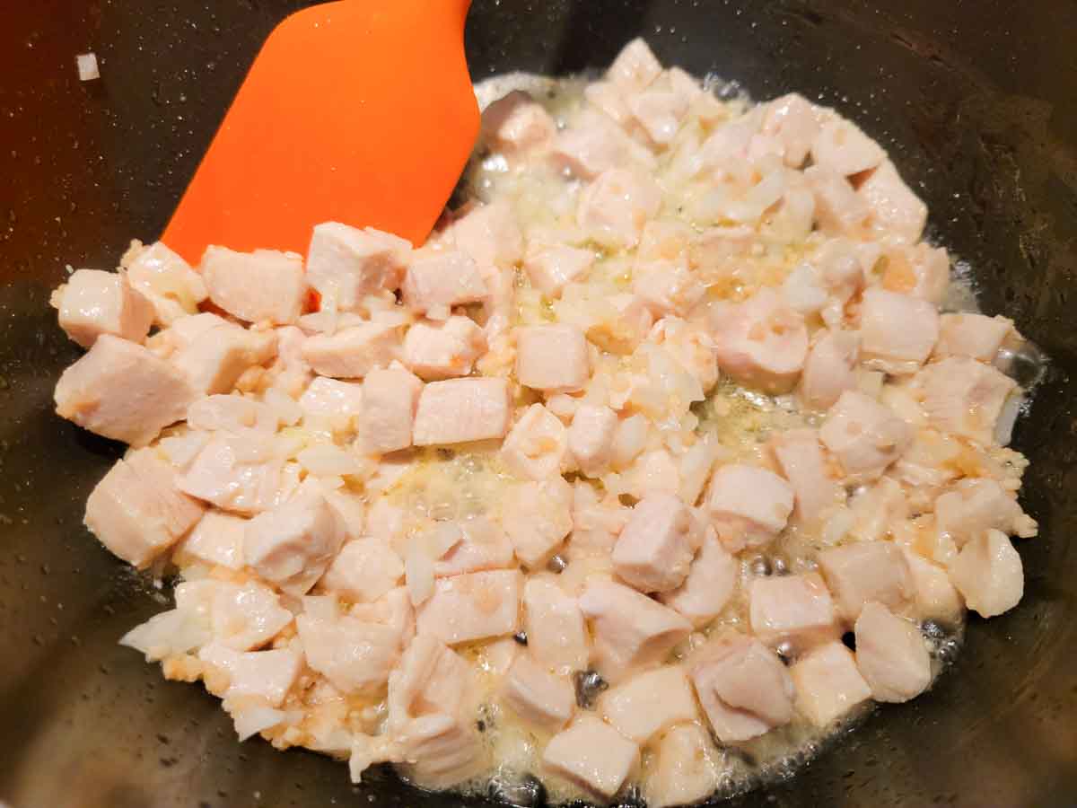 diced chicken and garlic cooking in a pan.