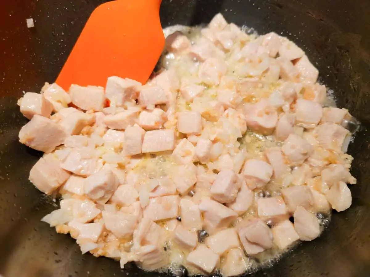 diced chicken and garlic cooking in a pan.