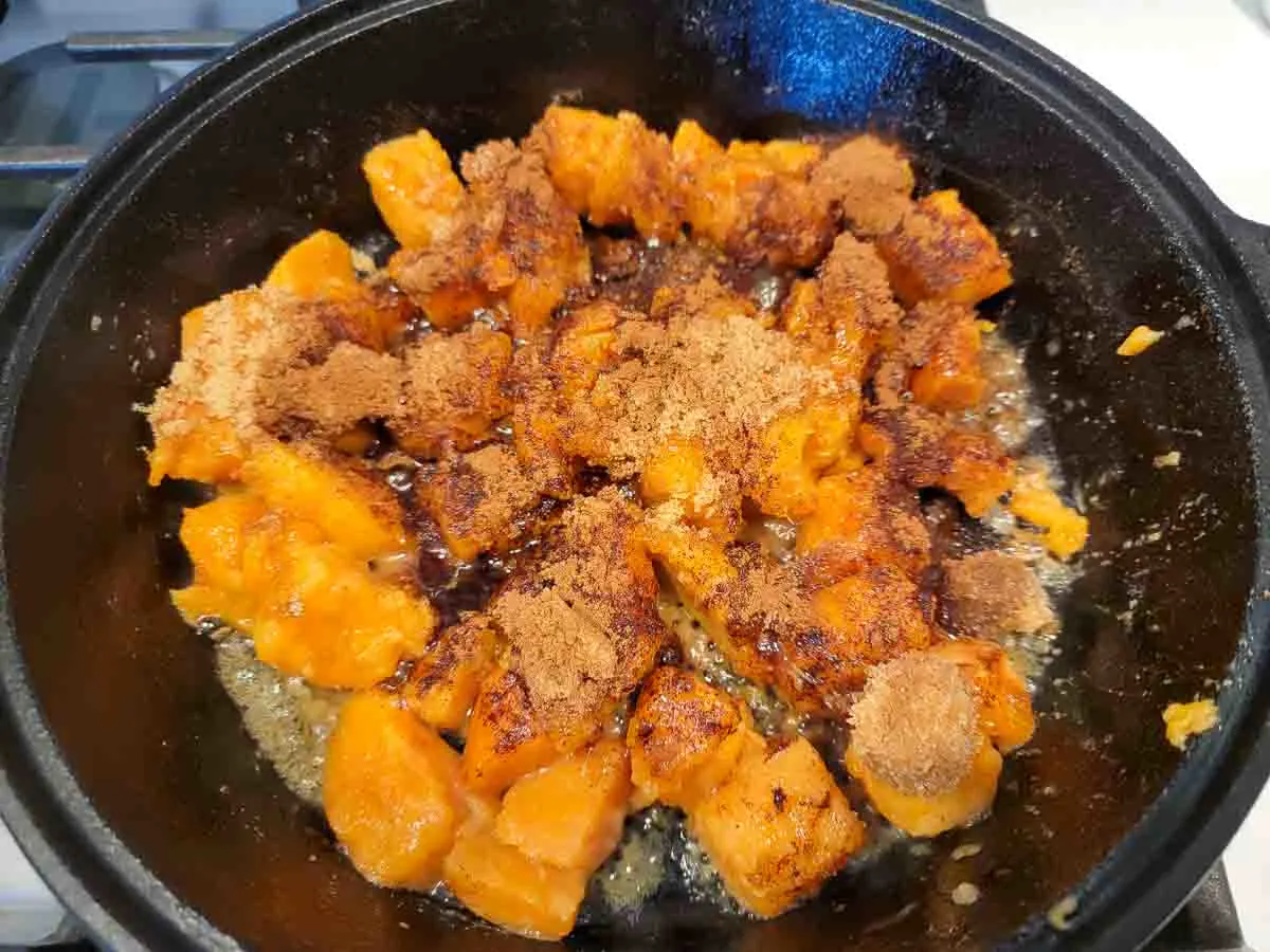 chopped sweet potatoes, cinnamon, butter, and brown sugar cooking in a skillet.