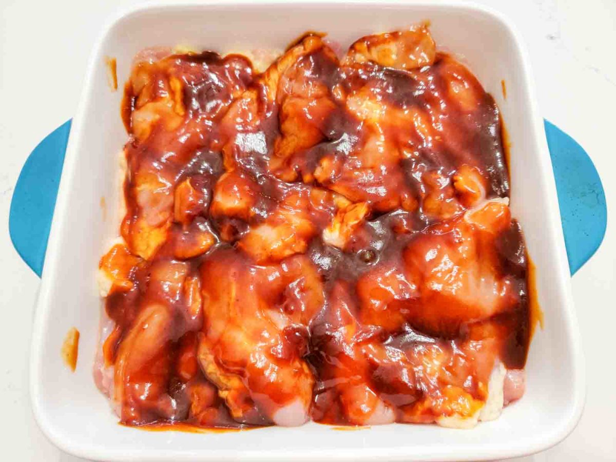 chicken thighs and bbq sauce in a baking dish.
