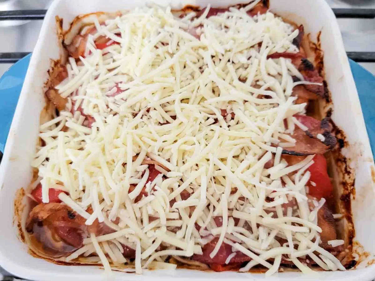 chicken thighs, roasted red peppers, bacon, bbq sauce, and shredded cheese in a baking dish.