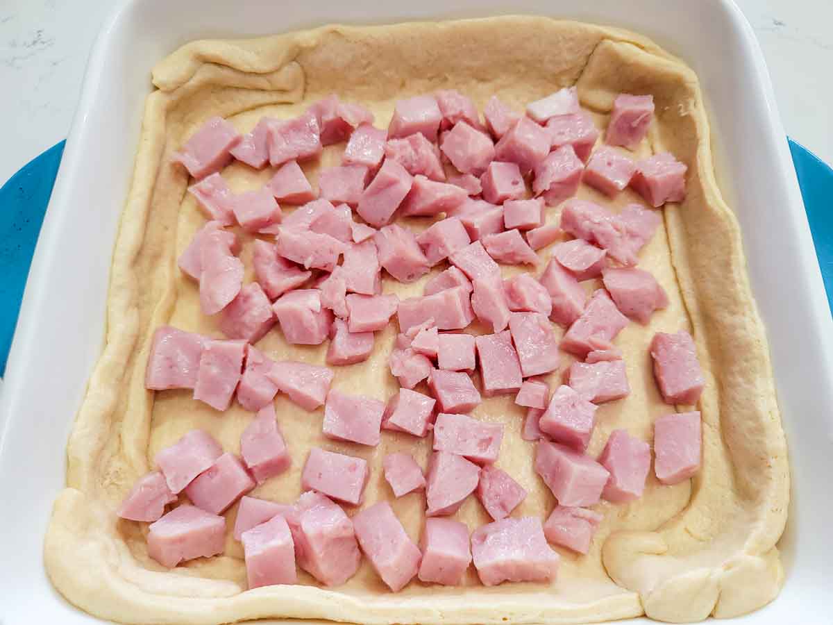 diced ham layered over crescent dough in a baking dish.