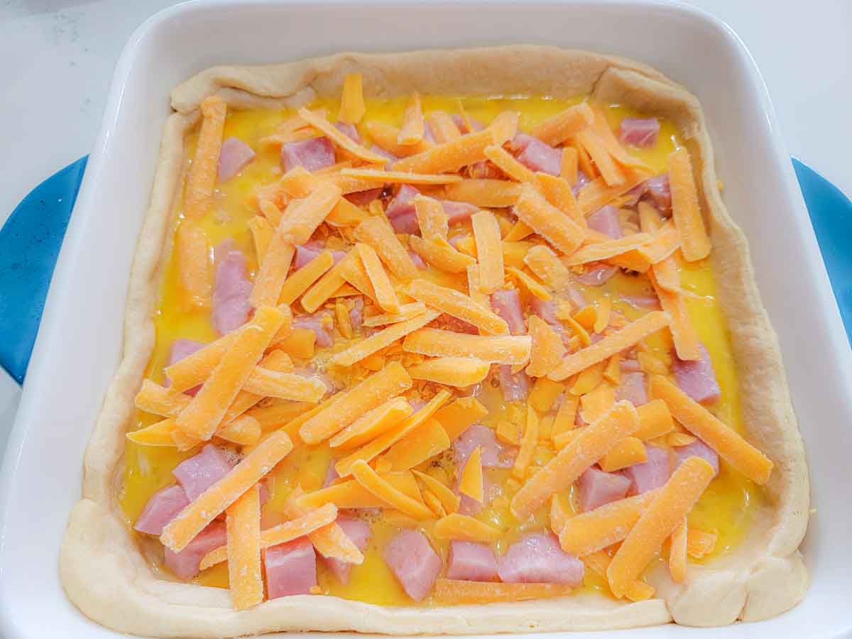 shredded cheese, beaten egg and diced ham layered over crescent dough in a baking dish.