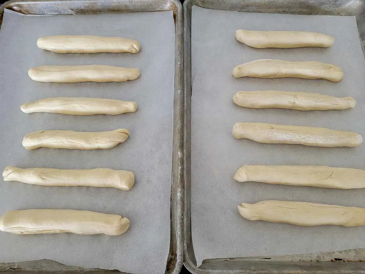 12 logs of breadstick dough on two baking sheets.