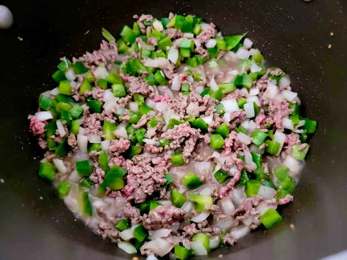 ground beef, onion, and green pepper cooking in a pan.