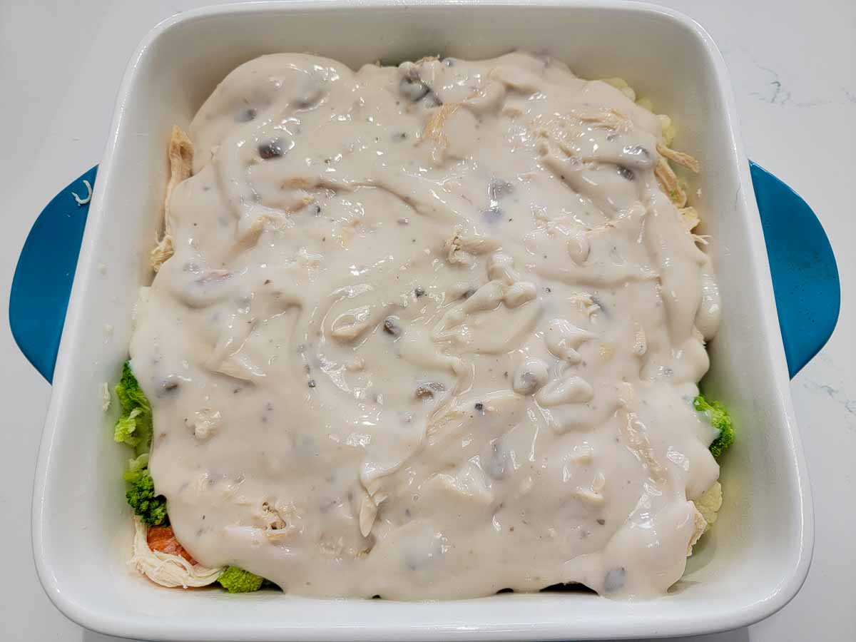 cream of mushroom soup, mixed vegetables and rotisserie chicken in a casserole dish.