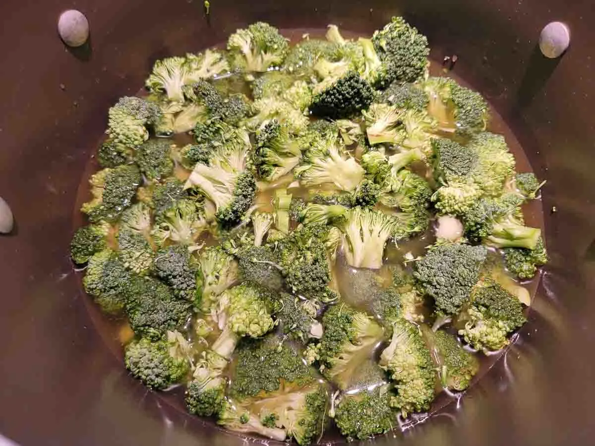 chicken broth, chopped broccoli, and onion powder cooking in a pan.