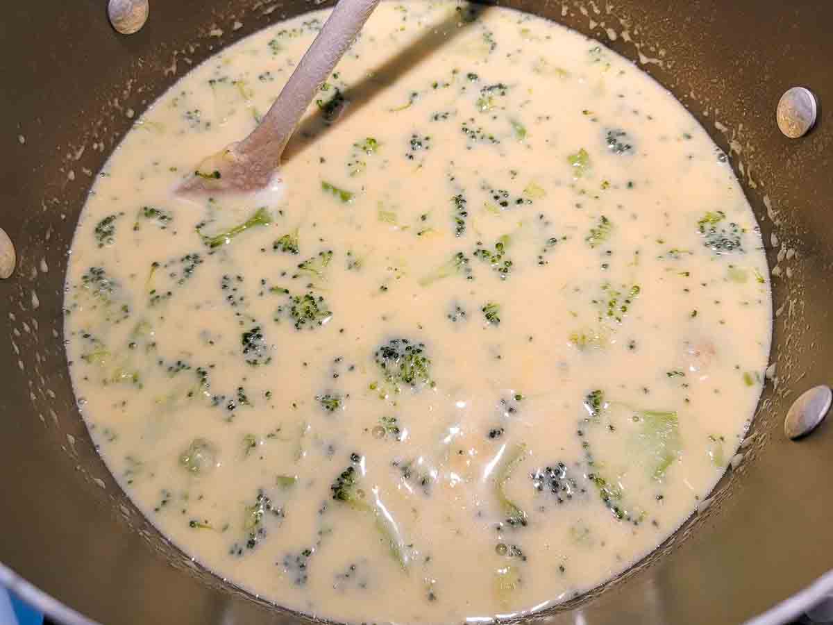 cheese sauce and broccoli cooking in a pan.