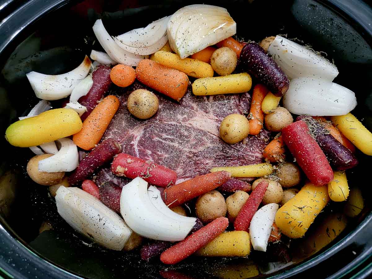 garlic, Worcestershire sauce, thyme, salt, pepper, beef roast, onions, potatoes, and carrots in a crockpot.
