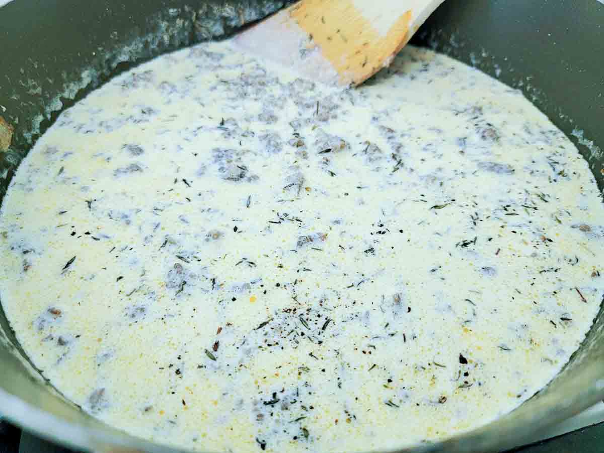 ground breakfast pork sausage, flour, butter, cream, thyme, and black pepper cooking in a pan.