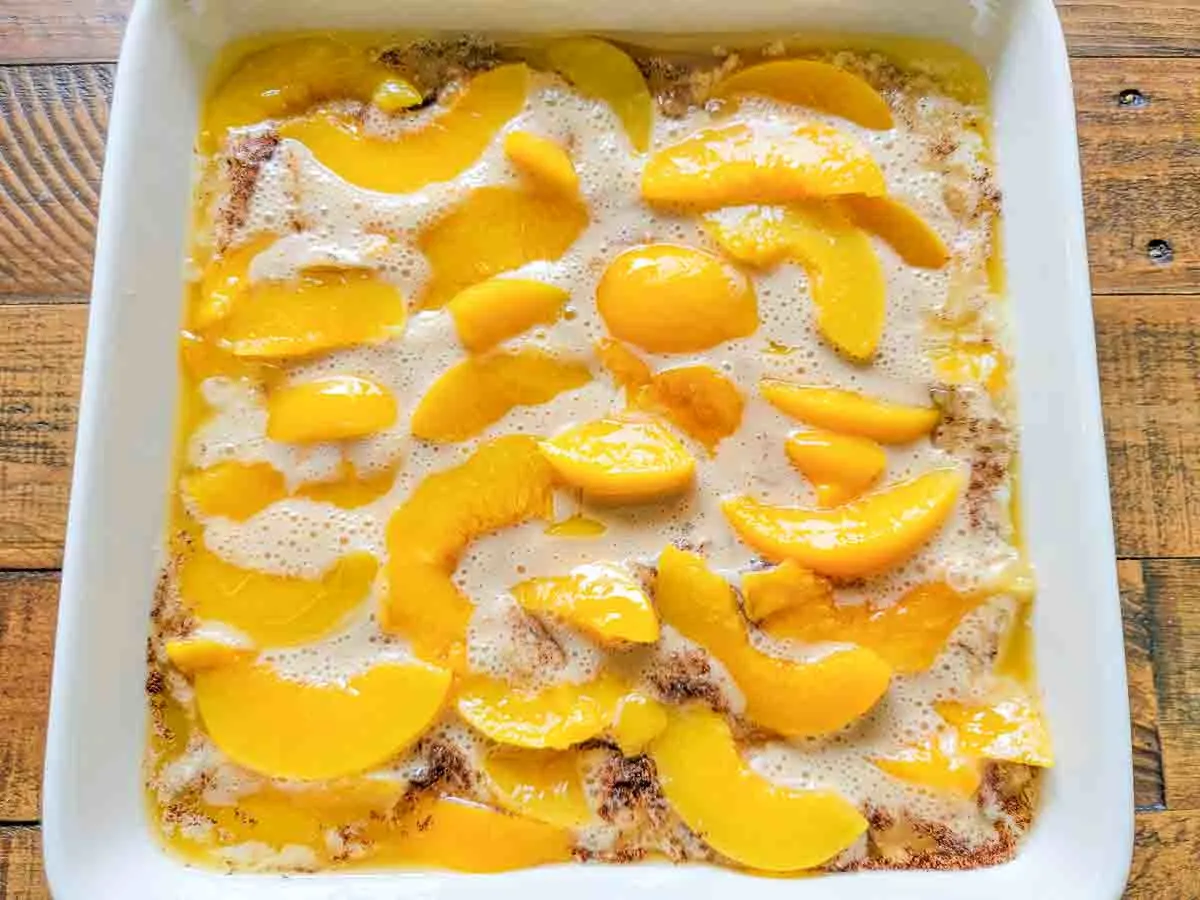 sliced peaches, batter, melted butter, and cinnamon in a baking dish.