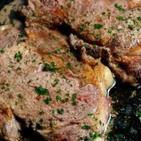 Cast Iron Skillet Ribeye Steaks cooking in a frying pan.