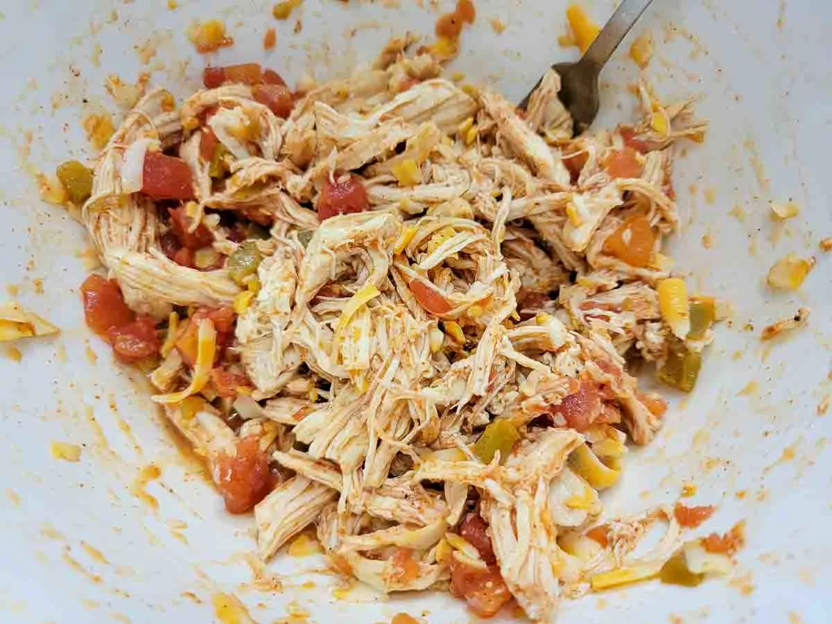 shredded chicken, Rotel tomatoes, taco seasoning, and cheese in a bowl.