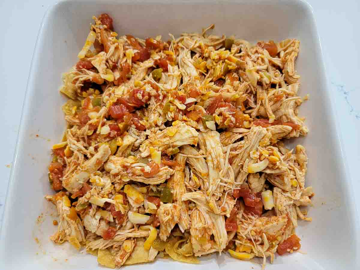 shredded chicken, Rotel tomatoes, taco seasoning, cheese, and crushed tortilla chips in a baking dish.