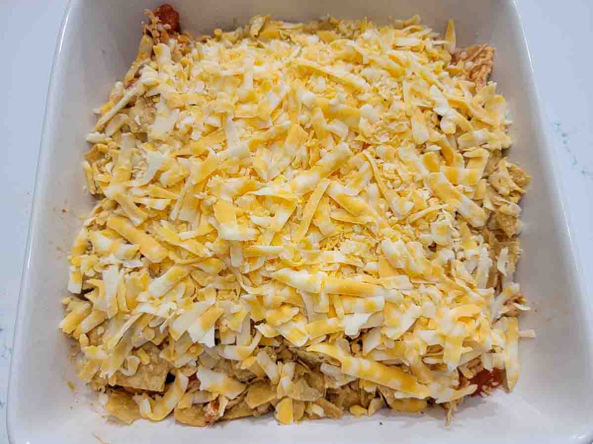 shredded chicken, Rotel tomatoes, taco seasoning, cheese, and crushed tortilla chips in a baking dish.