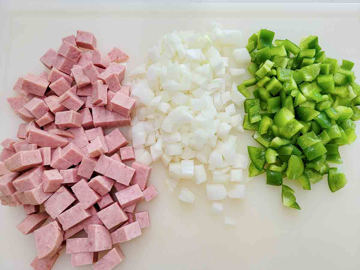 diced spam, onions, and green peppers on a cutting board.